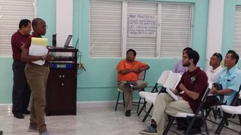 Volunteer standing up facing a group of people sitting in chairs