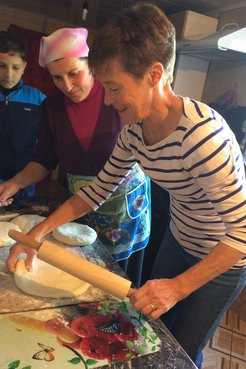 Woman rolling dough with person standing next to her