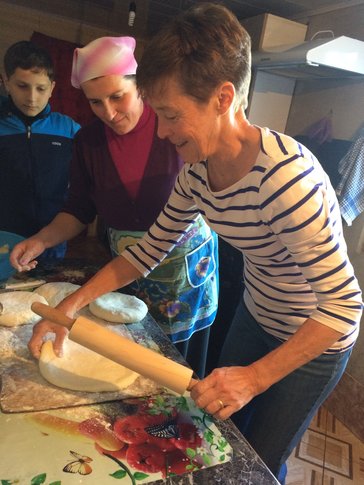 Woman rolling dough with person standing next to her