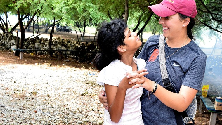 A volunteer and her young host sister hug and laugh