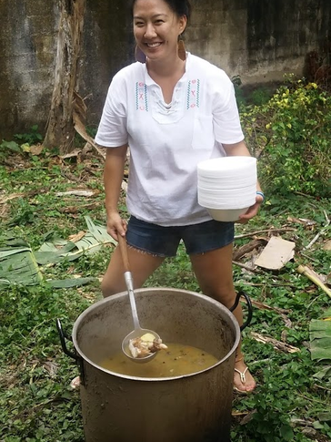 A Korean American woman stirs a big pot of soup outside