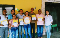 A group of people in Colombia stand outside smiling in front of a yellow wall.