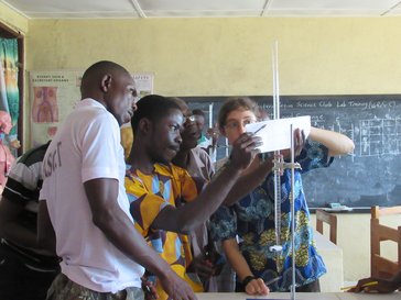 Teacher and student in front of white board conducting science experiment