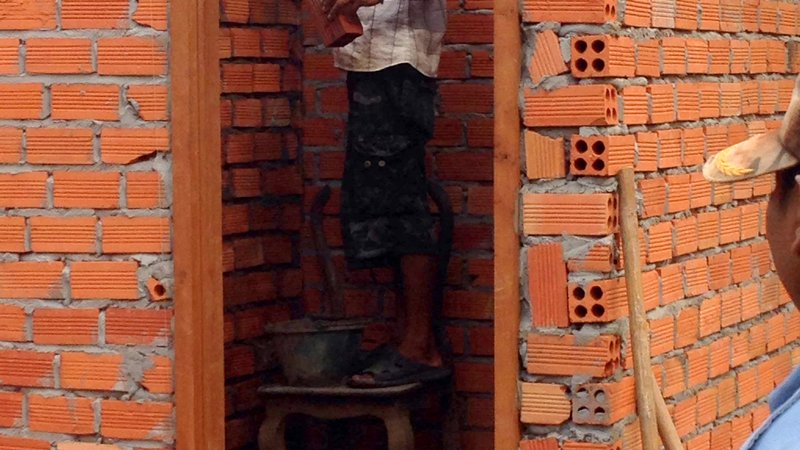Cambodia: A community member lays bricks for the new latrines.