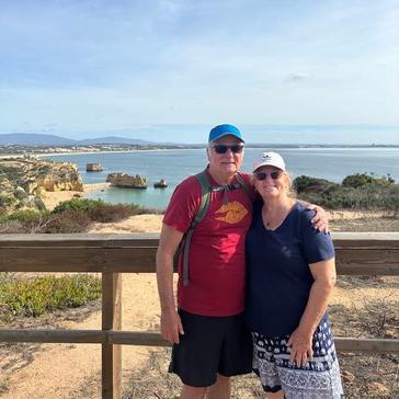 An older couple stand in front of a beach