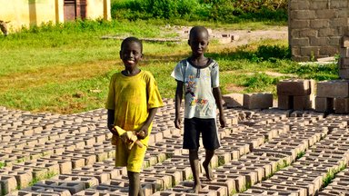 Local children walk across bricks made for the construction of the wall .jpg