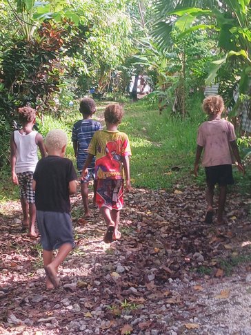 Local children escort Sally back to her kayak after literacy class.