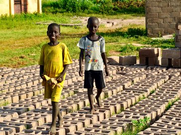 Local children walk across bricks made for the construction of the wall .jpg