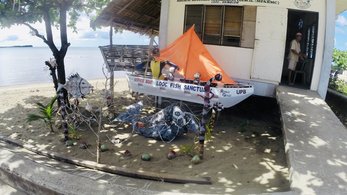 A little boat in front of a building on the beach- the Looc Fish Sanctuary
