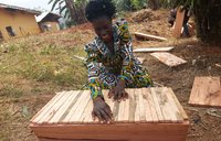 Madame Victorine Chia displays the beehive that she built after a technical session on hive construction