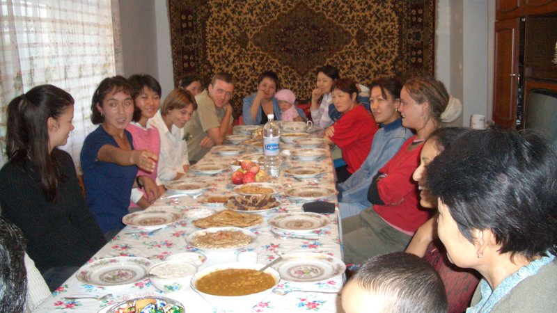 Mahima's family and host community sit and eat a traditional Indian meal together in Kyrgyzstan.