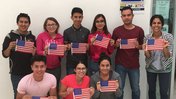 8 people holding up American flag