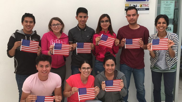 8 people holding up American flag