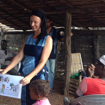 A female volunteer holds up a sign to show her neighbors the dangers of malaria