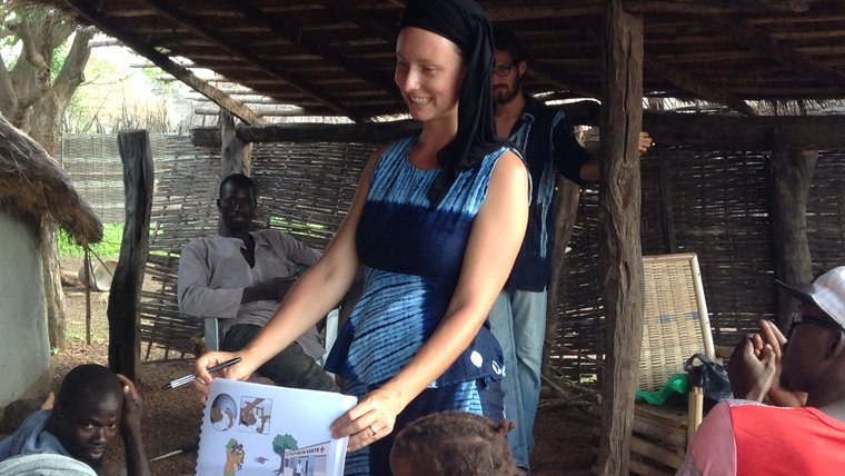 A female volunteer holds up a sign to show her neighbors the dangers of malaria