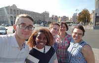 A group of people smile for a selfie on the streets of Ukraine.