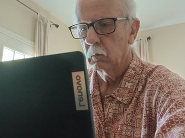 An older man faces a laptop screen.