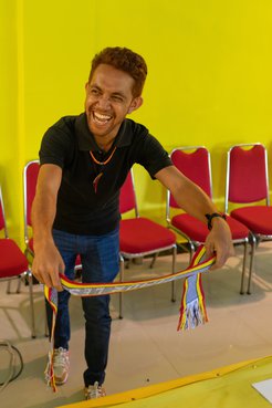 A man smiles holding a colorful sash