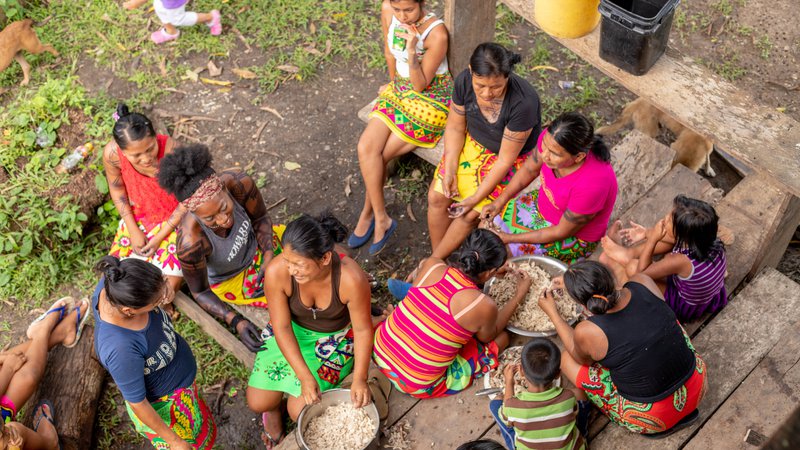A young, Black American woman and her Panamanian friends sit outside cooking together