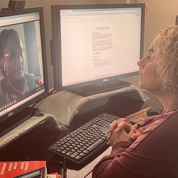 A blonde woman does a virtual meeting on her computer