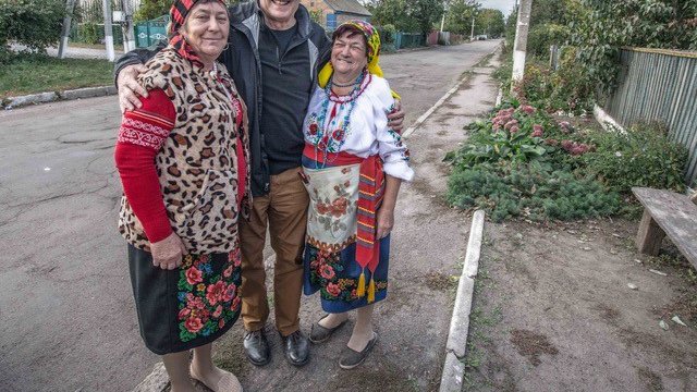 A white American male stands with his Ukrainian friends outside on a road