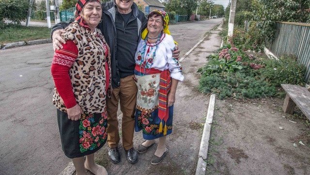 A white American male stands with his Ukrainian friends outside on a road