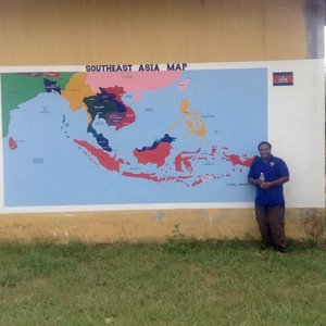 Volunteer stands in front of map mural