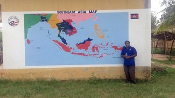 Volunteer stands in front of map mural