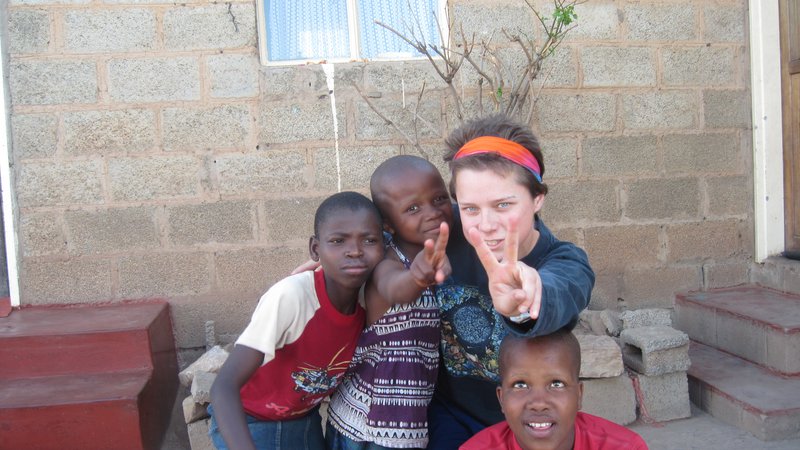 Young American woman poses playfully with three host sisters in Lesotho