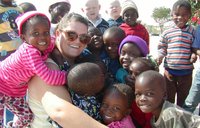 A female Volunteer joins a group hug with lots of her students.