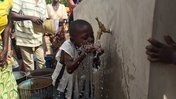 Community members and children gather to collect water from the solar powered filtration system.