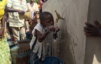Community members and children gather to collect water from the solar powered filtration system.