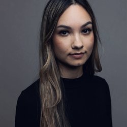 A headshot of a woman with long hair in a black long-sleeved shirt.