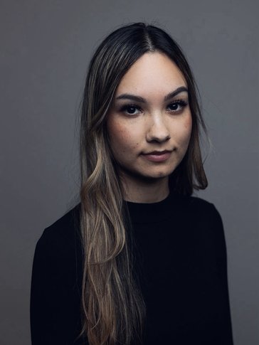 A headshot of a woman with long hair in a black long-sleeved shirt.