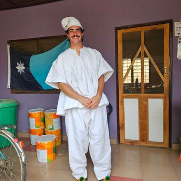 On his veranda, Austin wears the smock he received as a going-away present from members of his first Ghanaian community.