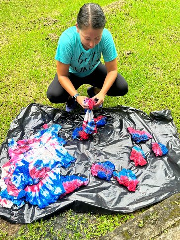 Students learn how to make tie-dye shirts with the colors of the Costa Rican flag for a community parade.