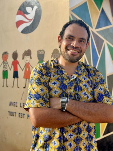 Sevi stands in front of a mural that showcases local artists' creativity in Togo.
