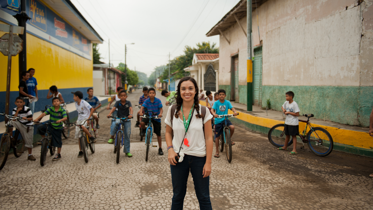 Female standing outside in front of kids on bikes