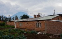 A rural Rwanda house in the foreground and a volcano in the background