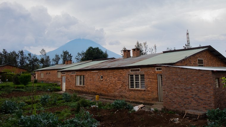 A rural Rwanda house in the foreground and a volcano in the background