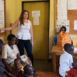 PCV Caroline stands in front of the women's group as she presents on oral rehydration salts.