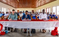 3 judges of the Speak Up! competition sit at a long table viewing the front of the classroom.