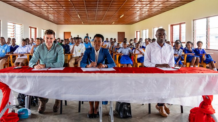 3 judges of the Speak Up! competition sit at a long table viewing the front of the classroom.