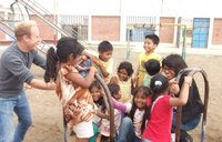 A volunteer plays with a group of kids on a merry-go-round.