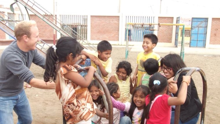 A volunteer plays with a group of kids on a merry-go-round.