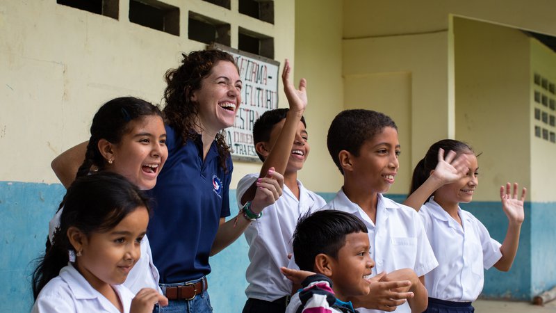 Woman in blue shirt surrounded by school children from Panama