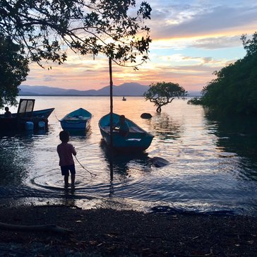 Two of our young neighbors play in their family's boat as the sun sets over the Guanacaste mountains.
