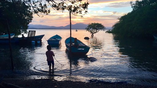 Two of our young neighbors play in their family's boat as the sun sets over the Guanacaste mountains.