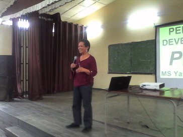 Woman stands with microphone in front of a projected presentation