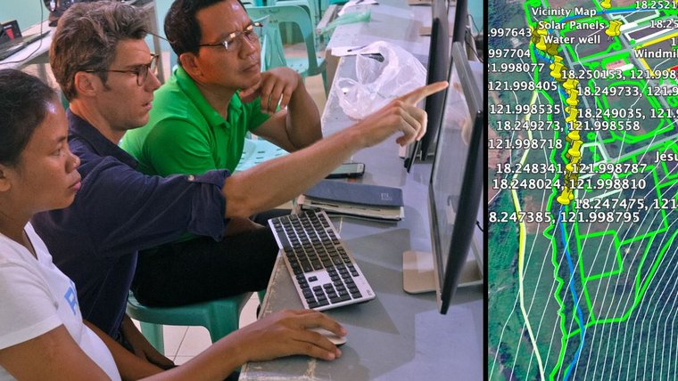 A American male sits with Filipino colleagues looking at a data map on a computer